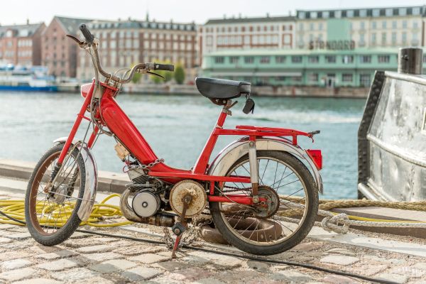 Rotes Mofa mit sichtbarem Oberflächenrost am Hafen