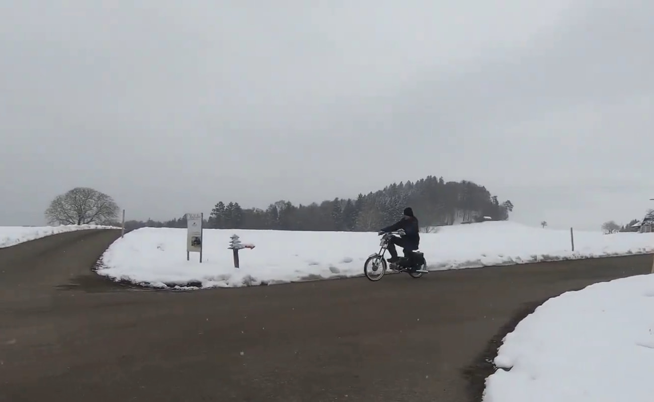 mofa-einwintern-beitragsbild Aufnahme von Mofa-Fahrer vor verschneiten Wiesen